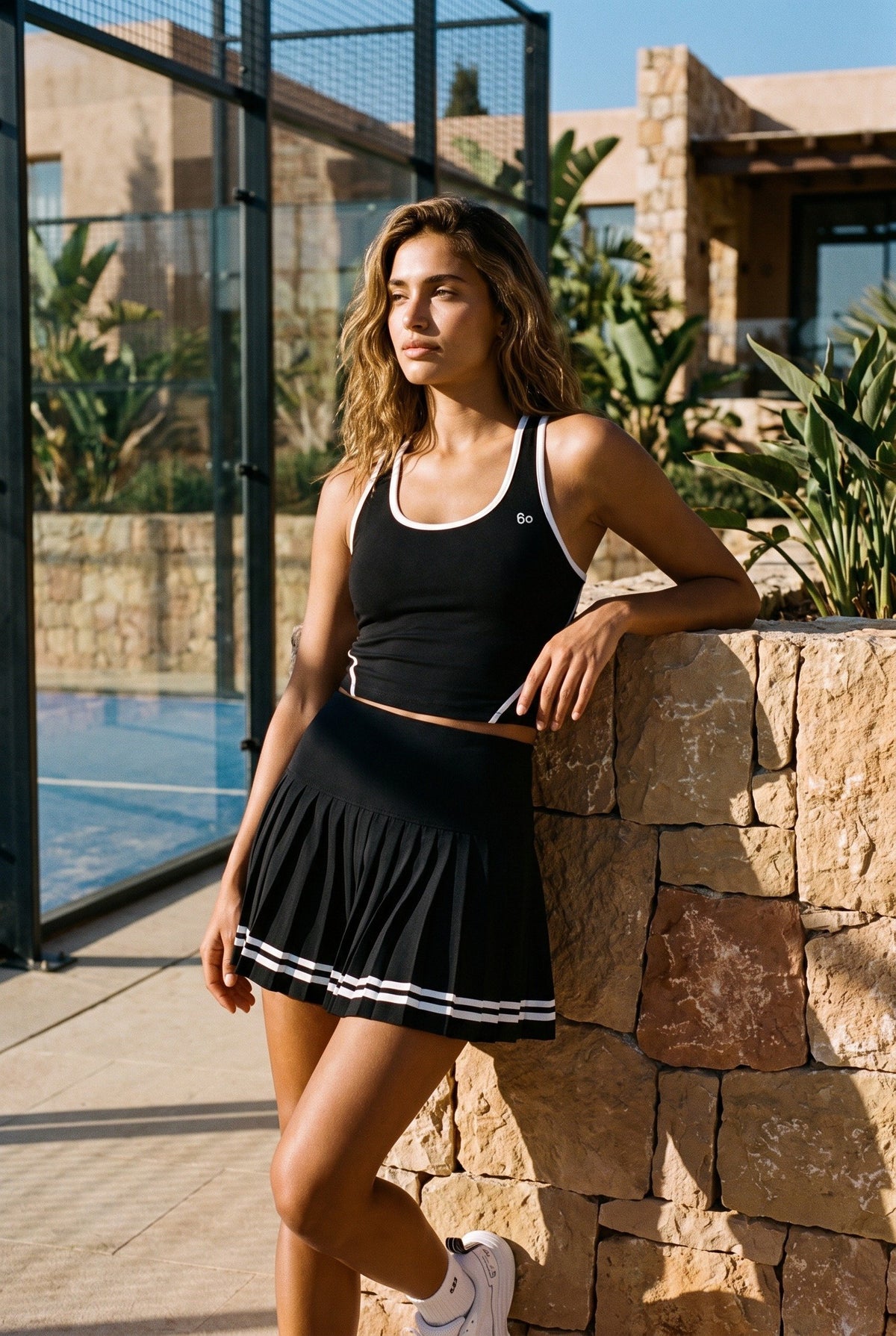 IVY tipped tank & pleated skirt set in Black – women's padel set by Six'o – lifestyle photo at the padel club