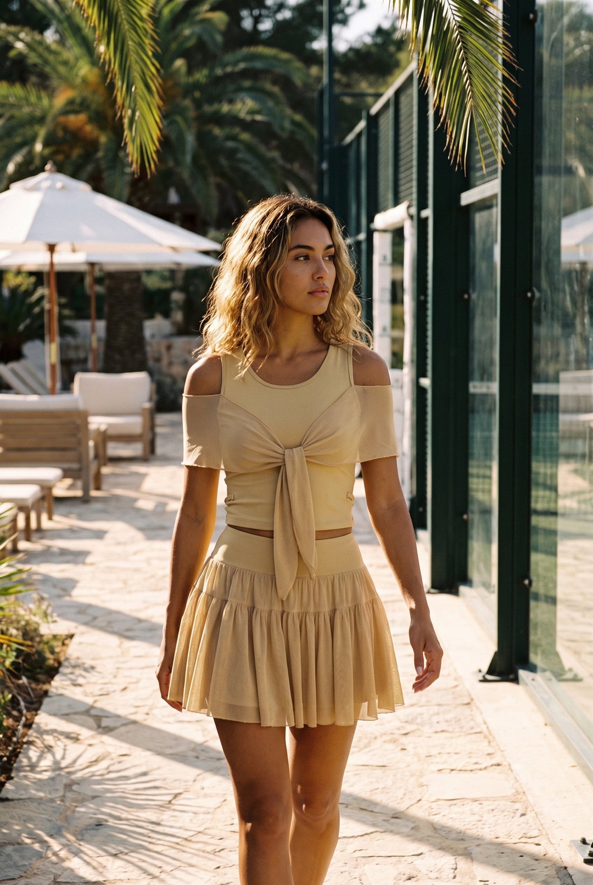 LILA cold-shoulder top & tiered skirt set in Almond yellow – women's padel set by Six'o – lifestyle photo at the padel club
