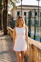 AMBER cross-back padel dress in White – women's padel dress by Six'o – lifestyle photo at the padel club