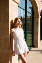 AMBER cross-back padel dress in White – women's padel dress by Six'o – lifestyle photo at the padel club