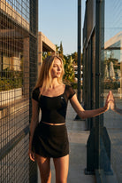 AVA mesh sleeve top & skort set in Black – women's padel set by Six'o – lifestyle photo at the padel club