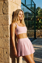 CORA bra top & pleated skirt set in Cream pink – women's padel set by Six'o – lifestyle photo at the padel club