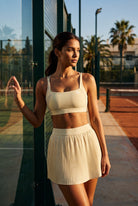 CORA bra top & pleated skirt set in Light Yellow – women's padel set by Six'o – lifestyle photo at the padel club