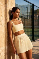 CORA bra top & pleated skirt set in Light Yellow – women's padel set by Six'o – lifestyle photo at the padel club