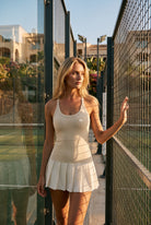 ELLA scoop neck pleated padel dress in Beige – women's padel dress by Six'o – lifestyle photo at the padel club
