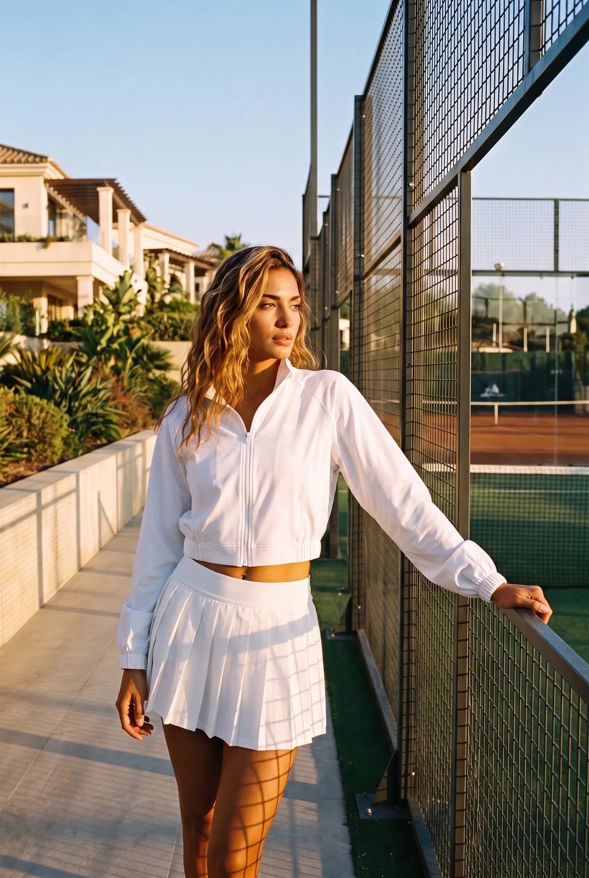 ELSA cropped jacket & pleated skirt set in White – women's padel set by Six'o – lifestyle photo at the padel club