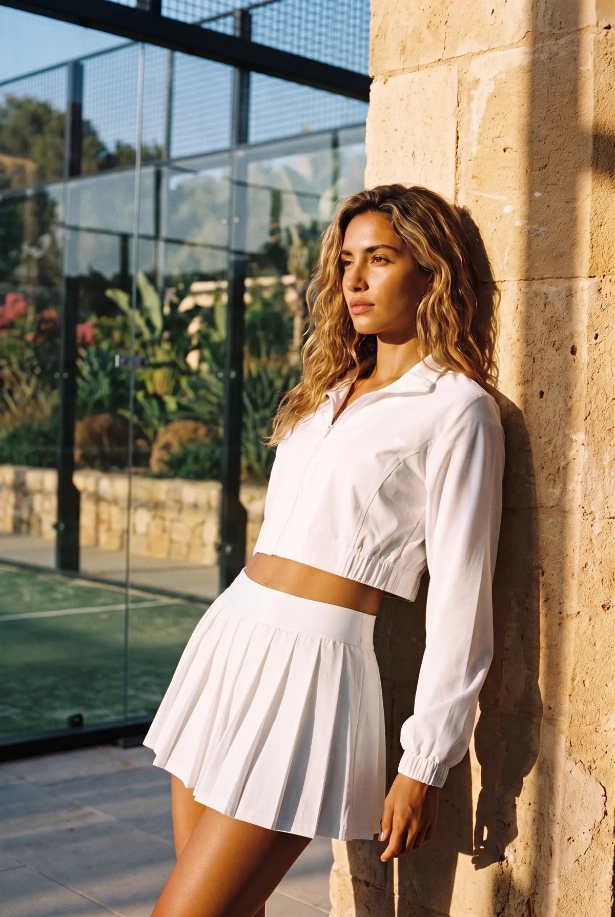 ELSA cropped jacket & pleated skirt set in White – women's padel set by Six'o – lifestyle photo at the padel club