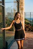 IVY tipped tank & pleated skirt set in Black – women's padel set by Six'o – lifestyle photo at the padel club