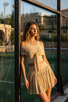 LILA cold-shoulder top & tiered skirt set in Almond yellow – women's padel set by Six'o – lifestyle photo at the padel club