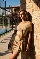 LILA cold-shoulder top & tiered skirt set in Almond yellow – women's padel set by Six'o – lifestyle photo at the padel club