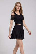 LILA cold-shoulder top & tiered skirt set in Black – women's padel set by Six'o – full-length studio photo