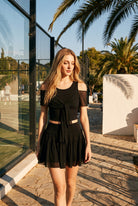 LILA cold-shoulder top & tiered skirt set in Black – women's padel set by Six'o – lifestyle photo at the padel club