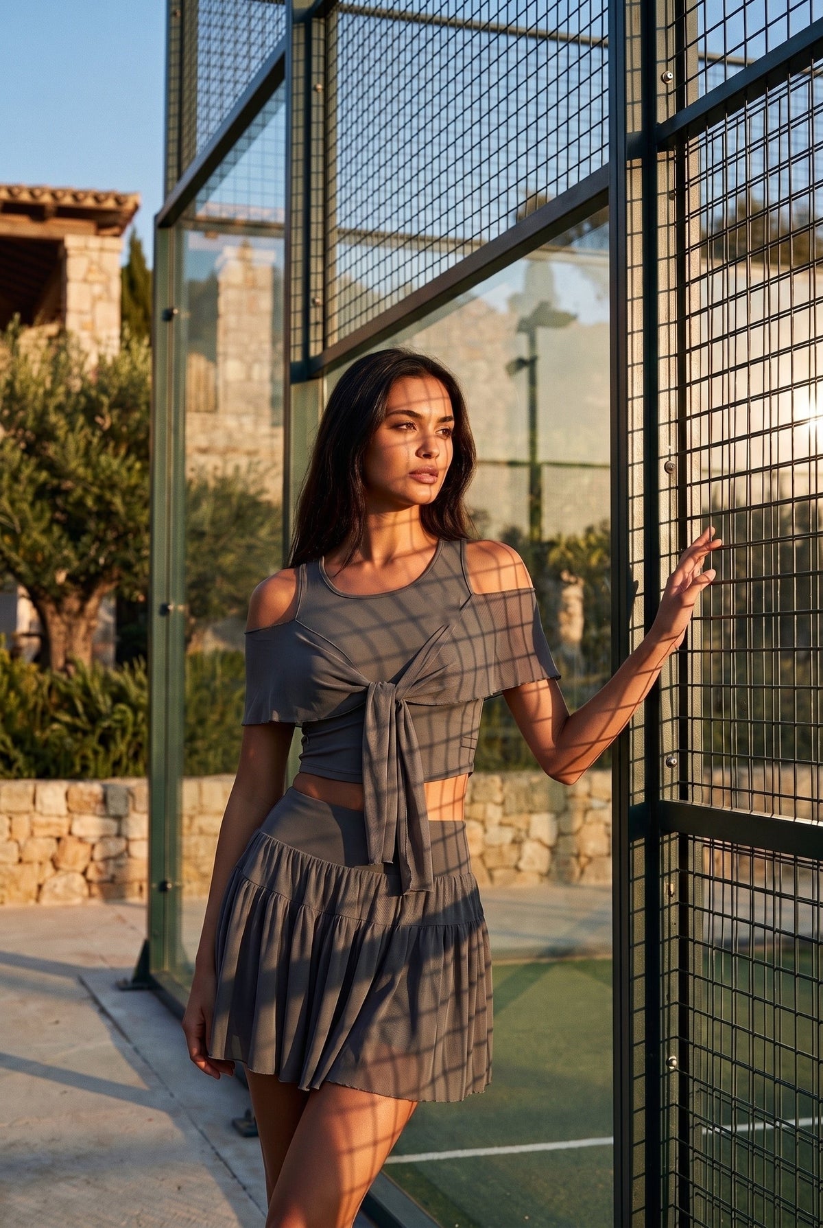 LILA cold-shoulder top & tiered skirt set in Grey – women's padel set by Six'o – lifestyle photo at the padel club