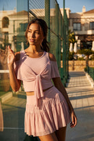 LILA cold-shoulder top & tiered skirt set in Primrose pink – women's padel set by Six'o – lifestyle photo at the padel club