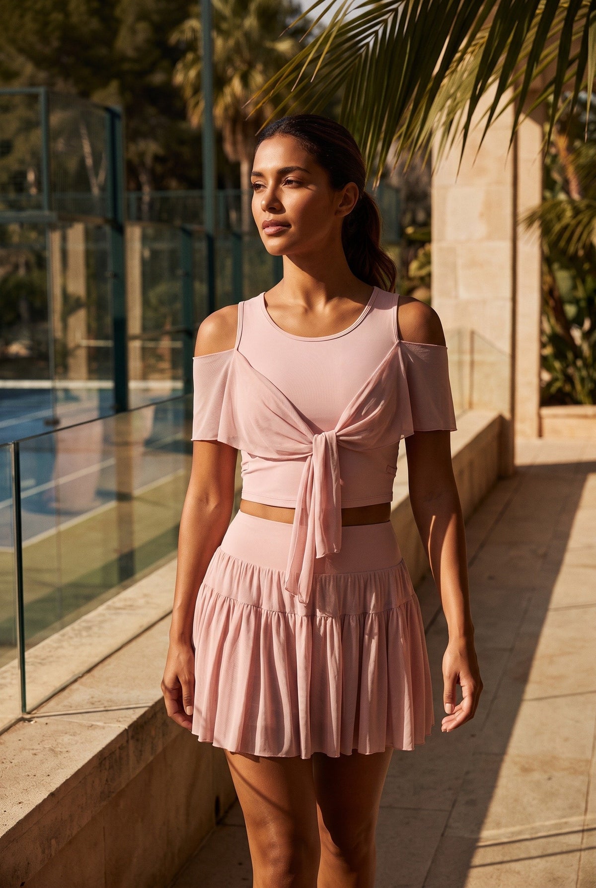 LILA cold-shoulder top & tiered skirt set in Primrose pink – women's padel set by Six'o – lifestyle photo at the padel club