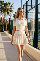 LILA cold-shoulder top & tiered skirt set in White – women's padel set by Six'o – lifestyle photo at the padel club