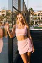 LIV bra top & wrap skirt set in Pink – women's padel set by Six'o – lifestyle photo at the padel club