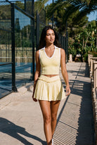 LUNA v-neck top & pleated skirt set in Yellow – women's padel set by Six'o – lifestyle photo at the padel club