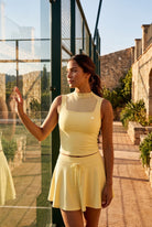 MAYA mesh tank & pleated skirt set in Pear yellow – women's padel set by Six'o – lifestyle photo at the padel club
