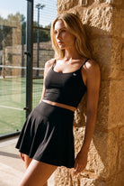 MILA cami bra & flare skirt set in Black – women's padel set by Six'o – lifestyle photo at the padel club