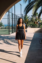 RUBY piped tank pleated dress in Black – women's padel dress by Six'o – lifestyle photo at the padel club