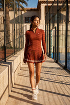 STELLA long sleeve & pleated skirt set in Rust red – women's padel set by Six'o – lifestyle photo at the padel club