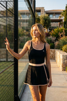 TARA tank top & trim skirt set in Black – women's padel set by Six'o – lifestyle photo at the padel club