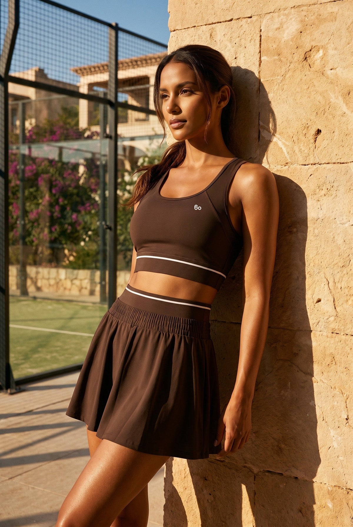 TESSA striped tank & pleated skirt set in Espresso brown – women's padel set by Six'o – lifestyle photo at the padel club