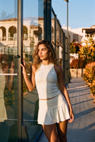 ZOE high neck padel dress in Heron white – women's padel dress by Six'o – lifestyle photo at the padel club