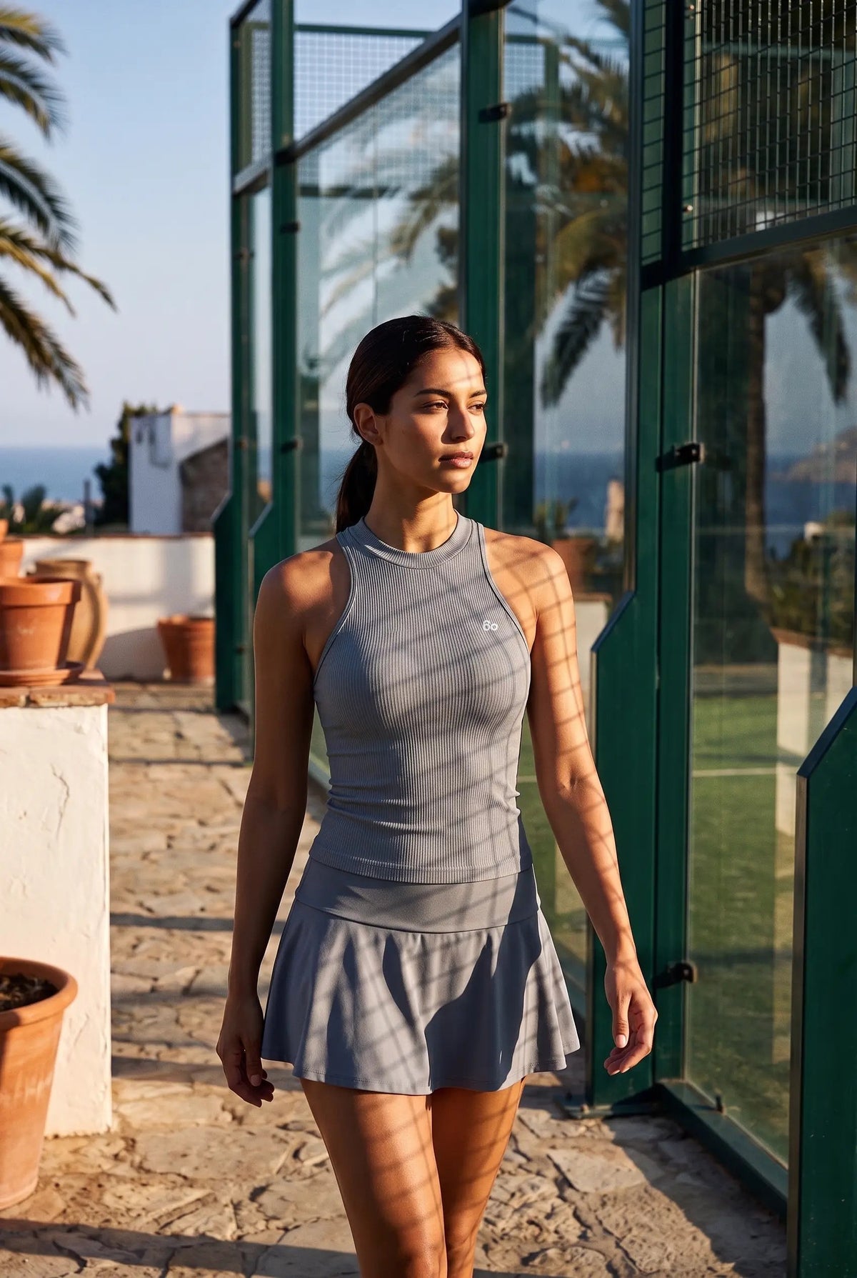 ZOE high neck padel dress in Pewter grey – women's padel dress by Six'o – lifestyle photo at the padel club